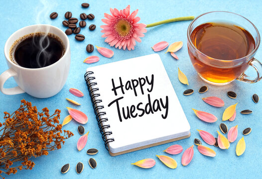 Happy tuesday written in a notebook with coffee tea and colorful flower petals around