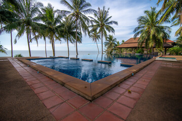 Fototapeta premium The swimming pool is located by the sea and is surrounded by coconut trees.