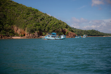 Fototapeta premium A tourist boat in the sea, with islands and mountains in the background.