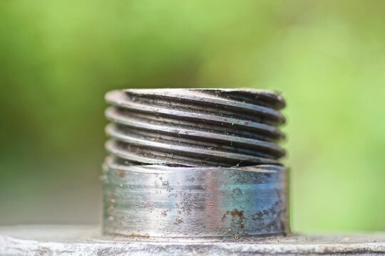 one detail from a part of a gray metal plumbing pipe with a thread on a green background