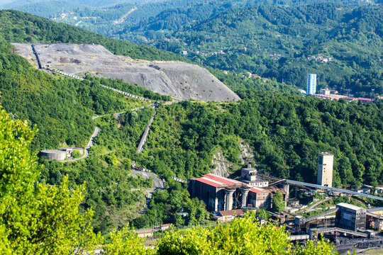 An aerial view of an industrial coal mining and processing facility nestled within a lush green forest landscape.