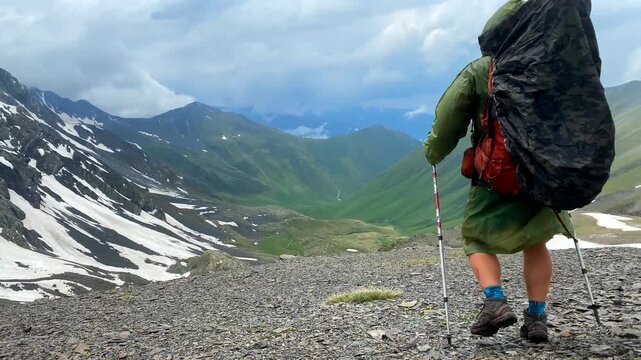 Tourist crosses Chaukhi Pass with a loaded backpack and trekking poles on a rocky alpine route in Georgia, representing high-altitude hiking, endurance travel, expedition planning and outdoor tourism