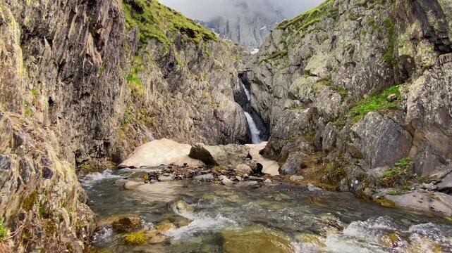 Snowmelt waterfall drains through a fractured mountain gorge near Chaukhi Pass in Georgia, documenting seasonal water supply, alpine hydrology, erosion processes and climate research conditions