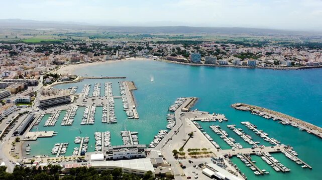 Aerial view of L'Escala Marina on the Costa Brava, featuring its modern harbor, sailing boats, breakwaters and the Mediterranean waterfront of this picturesque Catalan coastal town. 