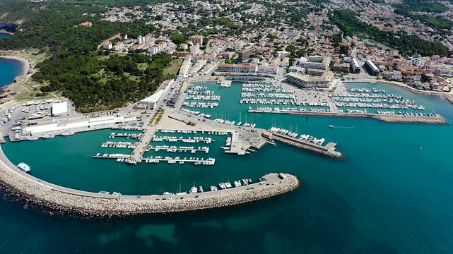 Aerial view of L'Escala Marina on the Costa Brava, featuring its modern harbor, sailing boats, breakwaters and the Mediterranean waterfront of this picturesque Catalan coastal town. 