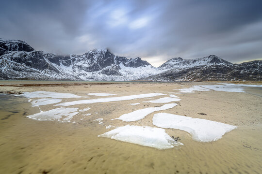 Ice structures glowing in last sunlight in sandy bay fjord Vareid