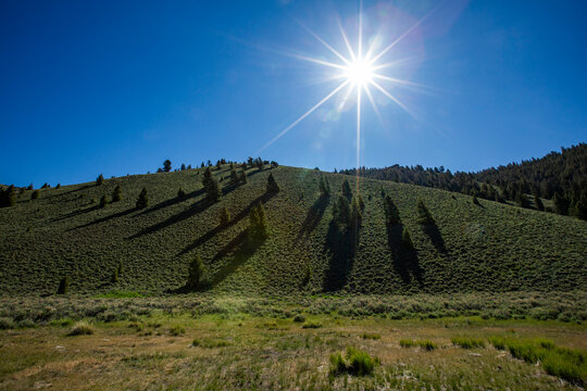 Sun on blue sky above green hill