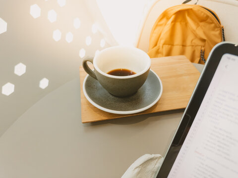 Empty Coffee Cup on Table Next to Digital Tablet and Backpack in Cafe Setting