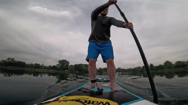 Man paddling SUP on cloudy lake