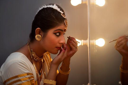 Mohiniattam dancer applying kajal in her eyes before performance