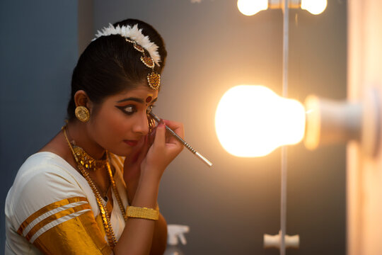 Mohiniattam dancer applying kajal in her eyes before performance