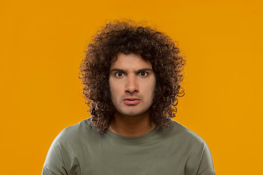 A YOUNG MAN WITH CURLY HAIR LOOKING ANGRY
