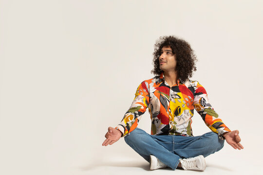 A YOUNG MAN WITH CURLY HAIR HAPPILY LOOKING ABOVE WHILE MEDITATING