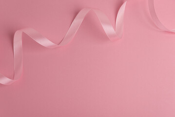 Pink satin ribbon creating elegant decorative border on solid background