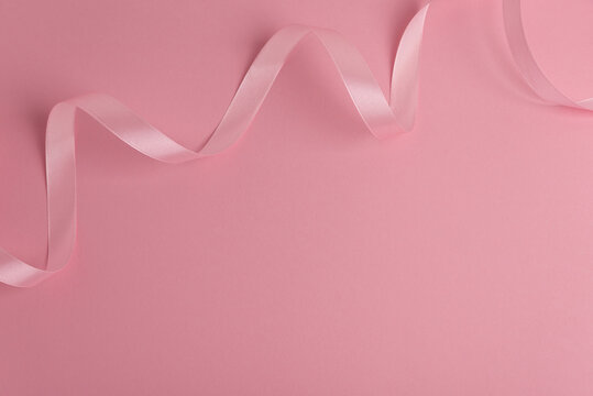 Pink satin ribbon creating elegant decorative border on solid background