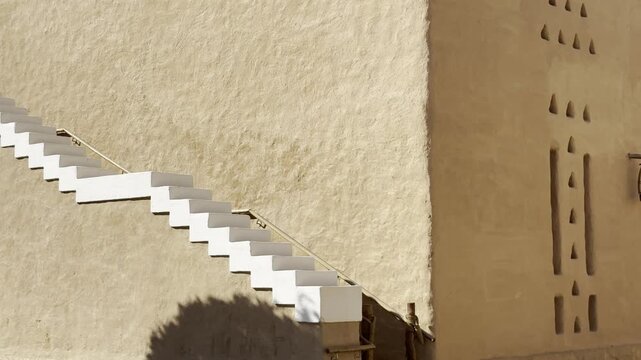 Close up view of white traditional stairs on mudbrick heritage wall with sunlight and shadows