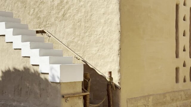 Close up view of white traditional stairs on mudbrick heritage wall with sunlight and shadows