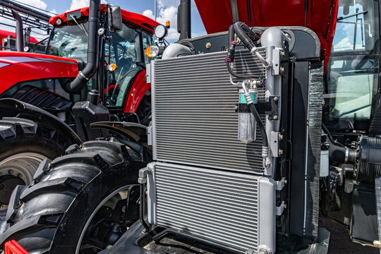 Agricultural tractor engine cooling radiators package. Modern farm machinery cooling system section with a c condenser, oil intercooler, receiver drier and industrial transport vehicle details.