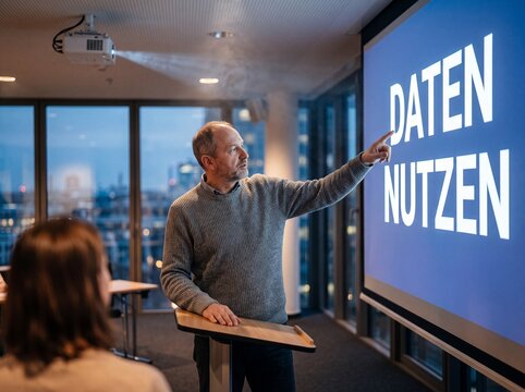 Mann mittleren Alters zeigt bei einer Pr&auml;sentation auf den Schriftzug DATEN NUTZEN auf einem Bildschirm