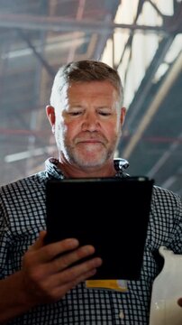 Mature, man and architect with tablet in warehouse for inventory inspection or distribution. Male person, contractor or checking stock with technology for construction, building supply or storage