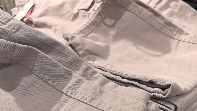 Stacks of trendy pants create a pleasing visual in this modern clothing shop. The colors range from classic black to soft grey, inviting customers to explore the latest fashion.