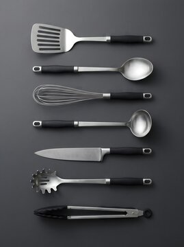 A collection of stainless steel kitchen utensils arranged neatly on a dark grey background.