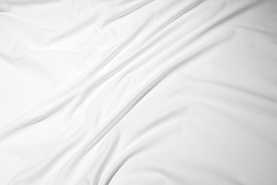 White wrinkled bed sheet with soft folds and subtle shadows creating a minimal, clean bedding texture. Neutral background ideal for product, lifestyle, interior, and textile design compositions