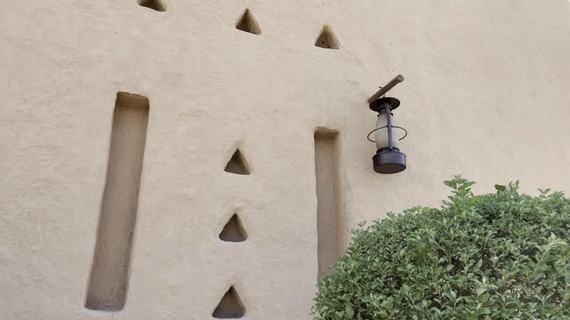 Close up view of traditional Najdi mudbrick wall with lantern and triangular ventilation openings