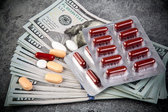 Pills and capsules on the background of dollar bills. Medicine concept