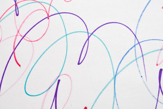 Abstract background of colorful felt tip pen scribbles and curved lines drawn on a white paper surface