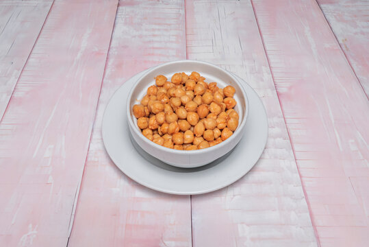 Bowl of Seasoned Chickpeas in Light Sauce Set on Plate Atop Whitewashed Table