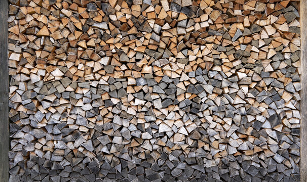 Gestapeltes Brennholz in verschiedenen Farbt&ouml;nen zwischen zwei Holzpfosten