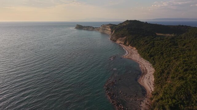 Wide drone view of a quiet beach, forested hills and clear Adriatic Sea along the coast of Kepi i Rodonit, Albania.

