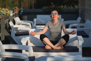 Fototapeta premium Woman Meditating In Lotus Pose On Outdoor Terrace