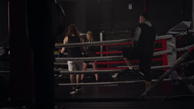 Young Caucasian female boxer entering boxing ring with middle aged Caucasian coach watching. Video suitable for fitness brand promotions and sports motivation content