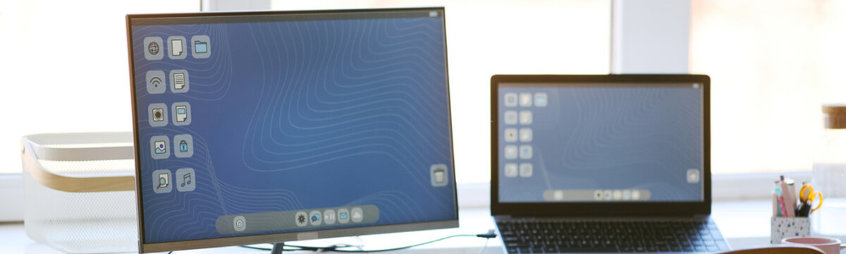 Wide shot of desktop monitor and laptop displaying matching interface, presenting connected digital workspace and cross device productivity. Ideal for technology marketing or software promotion