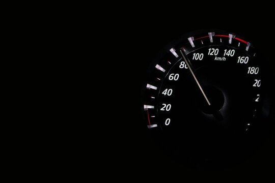 Illuminated car speedometer gauge on a dark dashboard showing speed around eighty kilometers per hour at night.