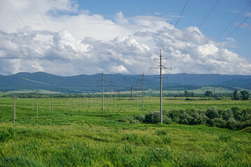 Obraz premium Power transmission lines across green Siberian valley