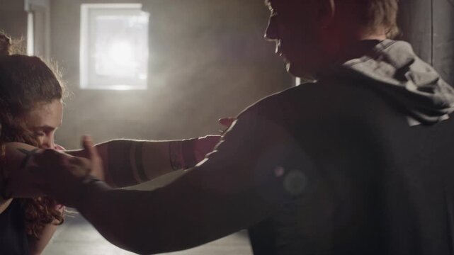 Caucasian middle aged male coach training Caucasian young female boxer in gym, correcting her punch posture. Ideal for fitness center promos and athletic training advertisements
