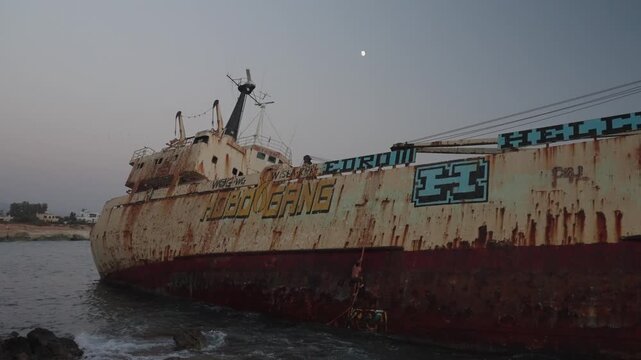 Rusty old shipwreck near the coastline on sunset