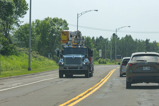 Quebec, Canada, 29 June 2026 : An International utility truck with a bucket lift drives on a road followed by other vehicles.