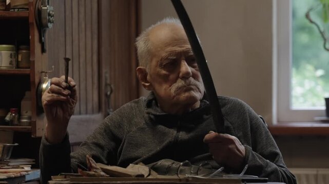 Elderly craftsman working in his old workshop, carefully restoring collectible Japanese bladed weapons