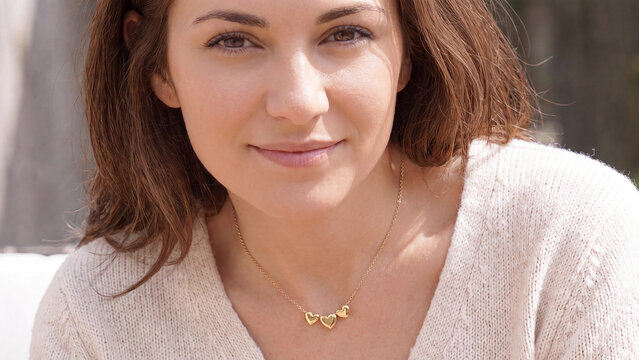 Smiling woman wearing a heart pendant necklace in warm natural light for romantic jewelry gifting and accessory retail marketing