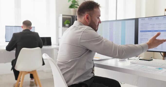 Operator agent provides support service by phone. In a bright office a professional works at a computer with dual monitors tracking spreadsheets and tasks. Focus on reliable service. 