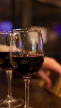Hand Collects Scratch Cards Beside Red Wine in Bar.