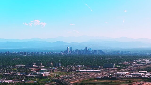 Front Range downtown cityscape city of Denver skyscrapers buildings Aerial drone view Colorado cars highway foothills Rocky Mountains layers summer spring haze clear blue skies morning forward up
