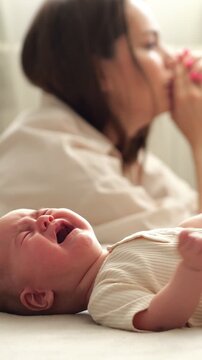 Frustrated and exhausted young mother experiencing postnatal depression and anxiety, unable to soothe her crying infant, representing the difficult reality of maternity and mental health