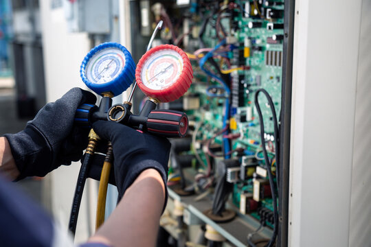 Air conditioning, HVAC service technician using gauges to check refrigerant and add refrigerant,Air Conditioning Repair, repairman on the floor fixing air conditioning system.