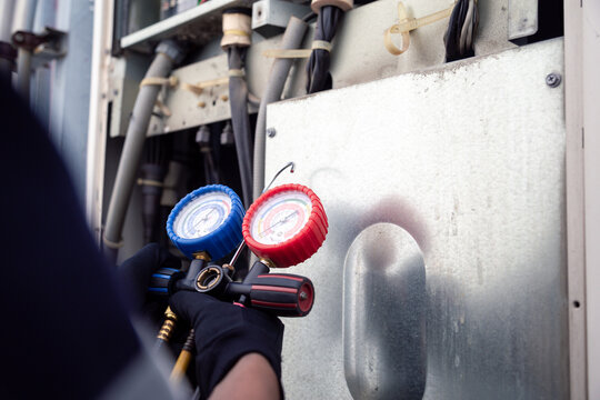 Air conditioning, HVAC service technician using gauges to check refrigerant and add refrigerant,Air Conditioning Repair, repairman on the floor fixing air conditioning system.