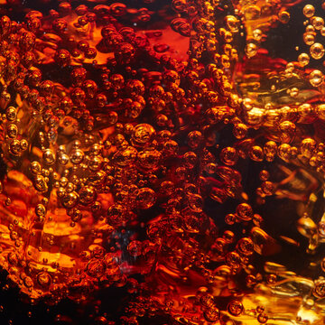 Sparkling soda bubbles rising in refreshing cola drink